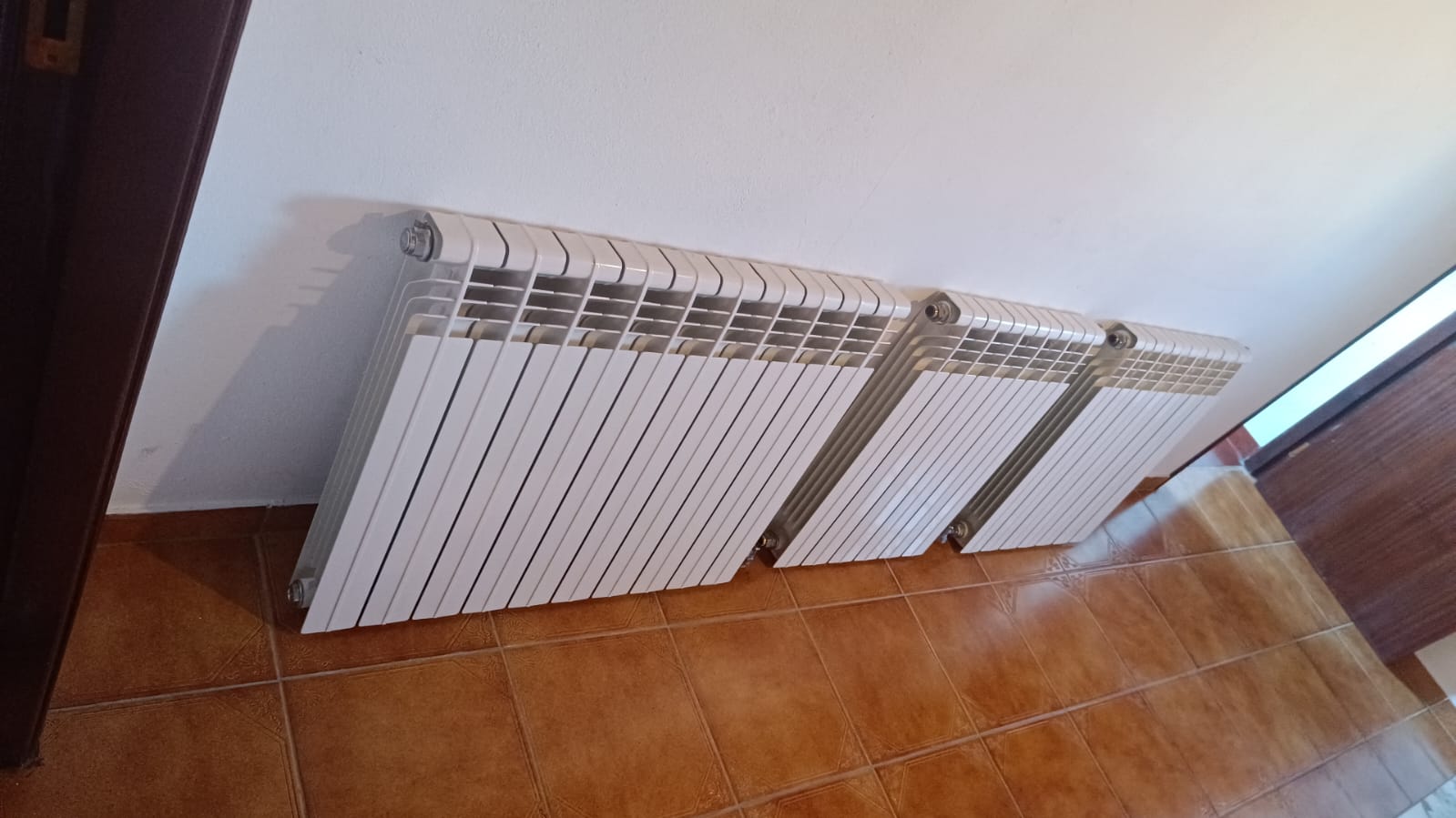 Radiador branco de aquecimento montado na parede junto a uma janela