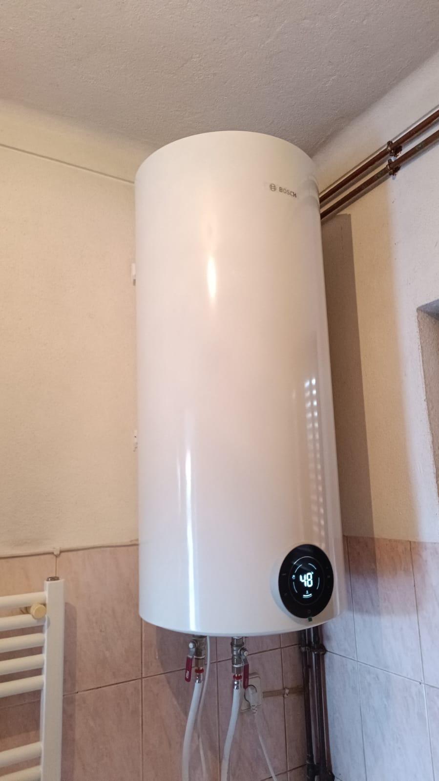 Termoacumulador elétrico branco montado verticalmente na parede