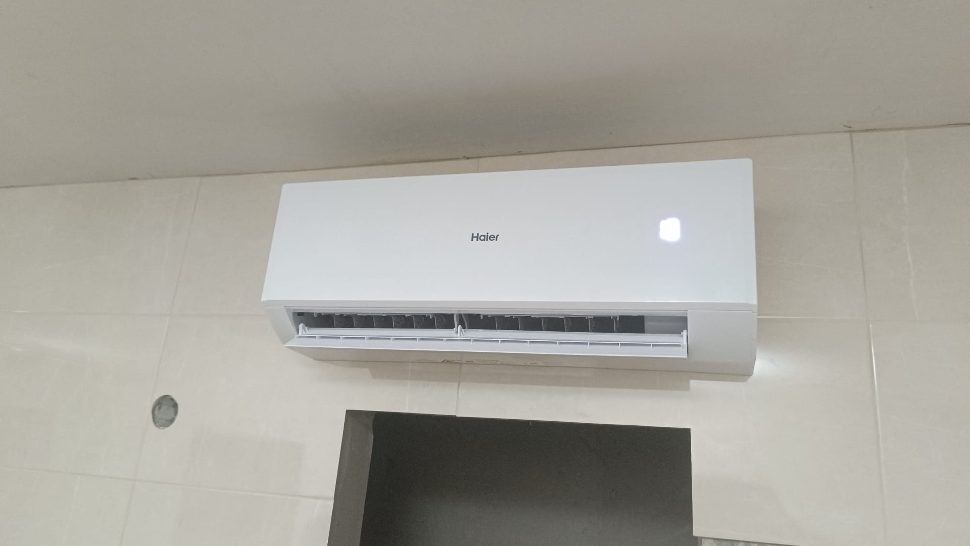 Unidade interior de ar condicionado Haier numa parede revestida a azulejo